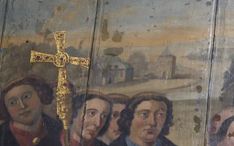 A 16th century painting from Chichester Cathedral, depicting several men carrying a golden cross. Faintly, in the background, buildings can be seen sitting on the coastline. One has a cross on its roof.