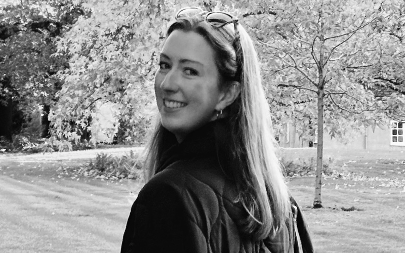 a black and white image of a woman in a park looking back at the camera