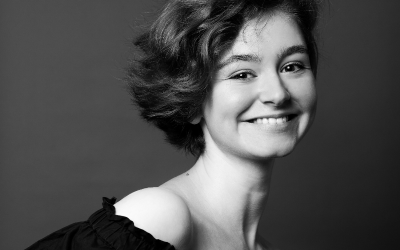 a black and white photo of a woman with short, wavy dark hair smiling at the camera