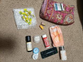 3.	This is an image of a pink clutch with the objects presented: cough sweets, tylenol, sewing kit, ear plugs, strip of tablets, tissues, essential oil, container for contact lenses. 