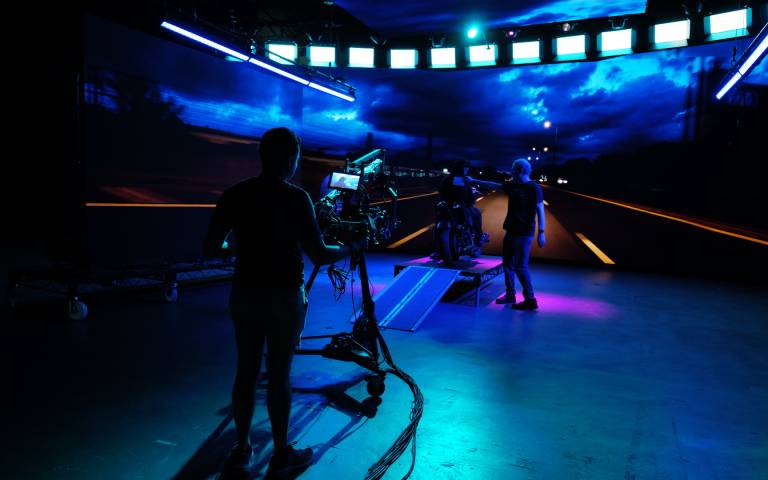 Camera operator in a media studio, lit in atmospheric blue lighting