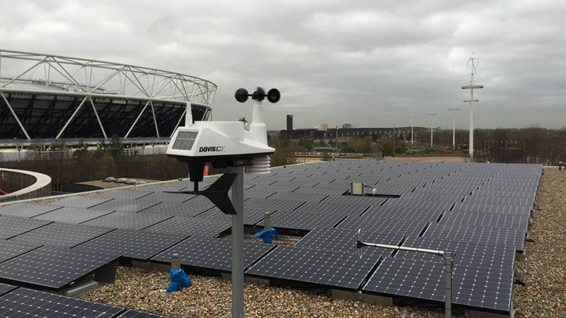 Remote sensing device powered by solar panels pointed towards an urban development