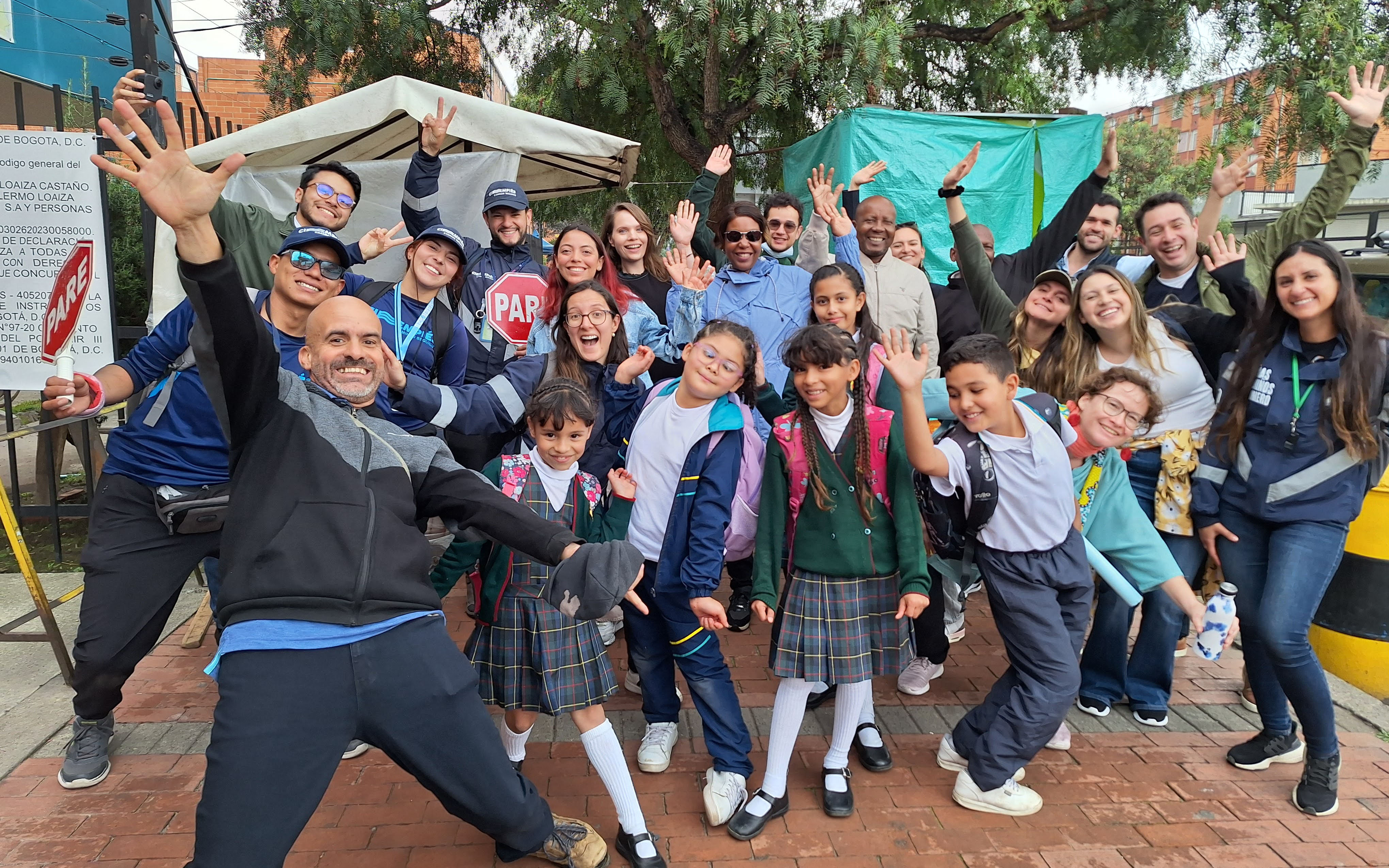 Group of students and teachers smiling at the camera with hands outstretched 