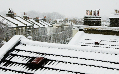Photograph of the roofs of terraced houses covered in snow on a cold and snowy day