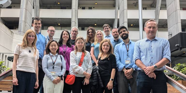 The PAICE team standing together and smiling infront of some building steps at UCL.