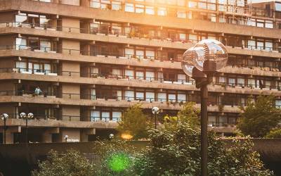 A lamppost in front of the terraces of the Barbican, London. The sunlight is coming from the top and as it's setting it's reflecting on the glass globe of the lamppost. 