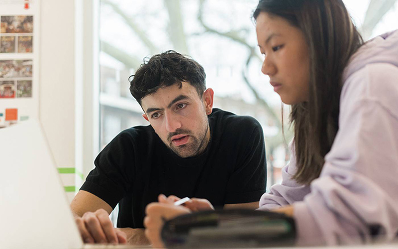 Two students working together on a laptop