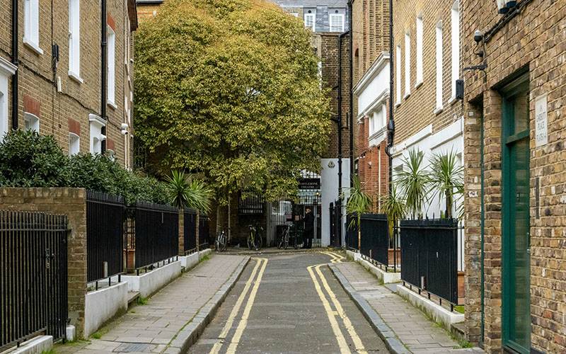 A street in London with houses either side and a tree at the end of the road