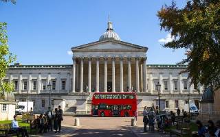 Main campus of UCL. There is a large red bus parked in front of the main building.