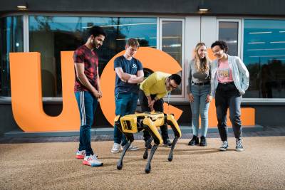 Five students outside UCL East with a robot dog