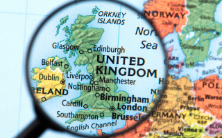 A magnifying glass hovering over the United Kingdom on a map.