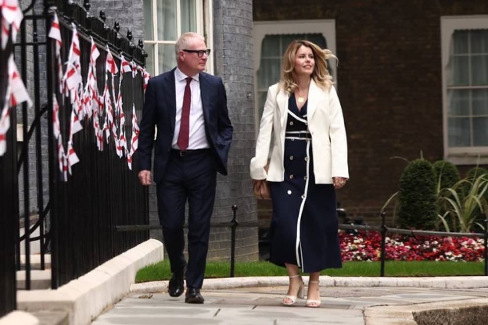 Mayor Richard Parker and Mayor Kim McGuiness walk down Downing Street towards Number 10. Both are looking to the right. To the left, black railings are covered in small England flags (a red cross on a white background).