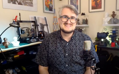 A person in glasses sits at a microphone ready to record a video or podcast.