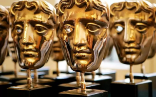 Gold Bafta trophies on a desk.