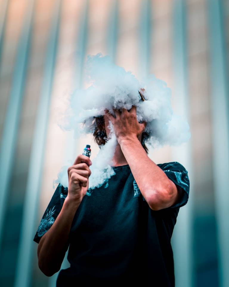 Teenager vaping with vapours surrounding his face