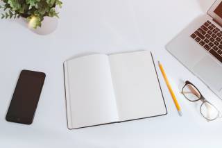 image of a book, laptop, phone, pencil, and glasses on a desk