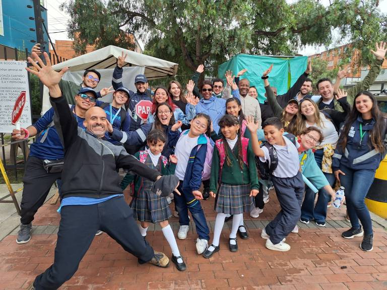 On the Way to School staff and school children in Colombia gathered together with arms in the air and happy smiles.