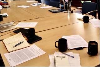 A table with open notebooks and coffee cups