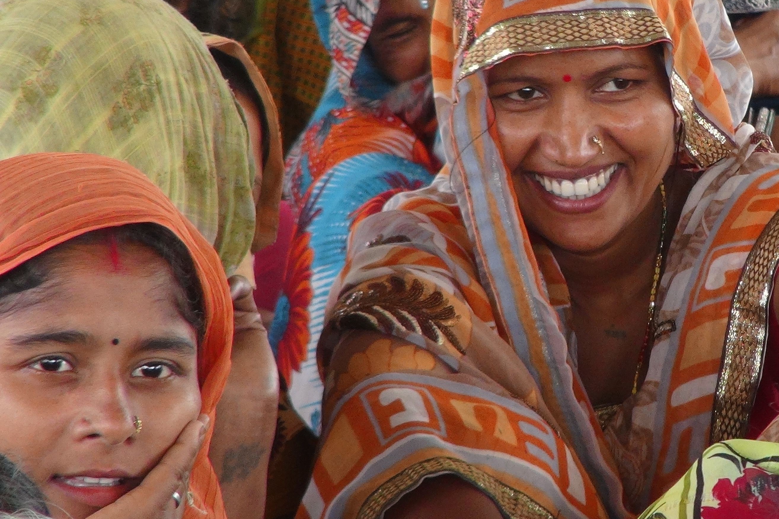 Two women in saris smiling at the camera 