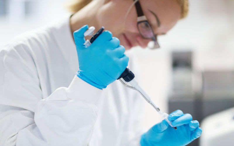 Female researcher pipetting liquid in to a PCR tube 