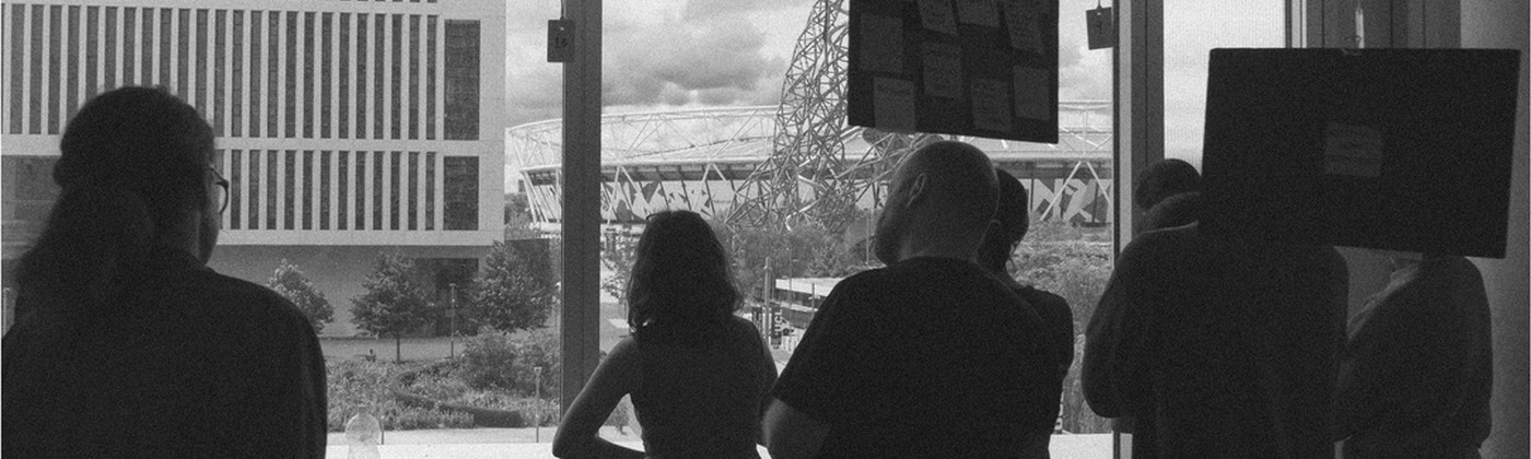 Black and white image of people looking out onto a urban landscape