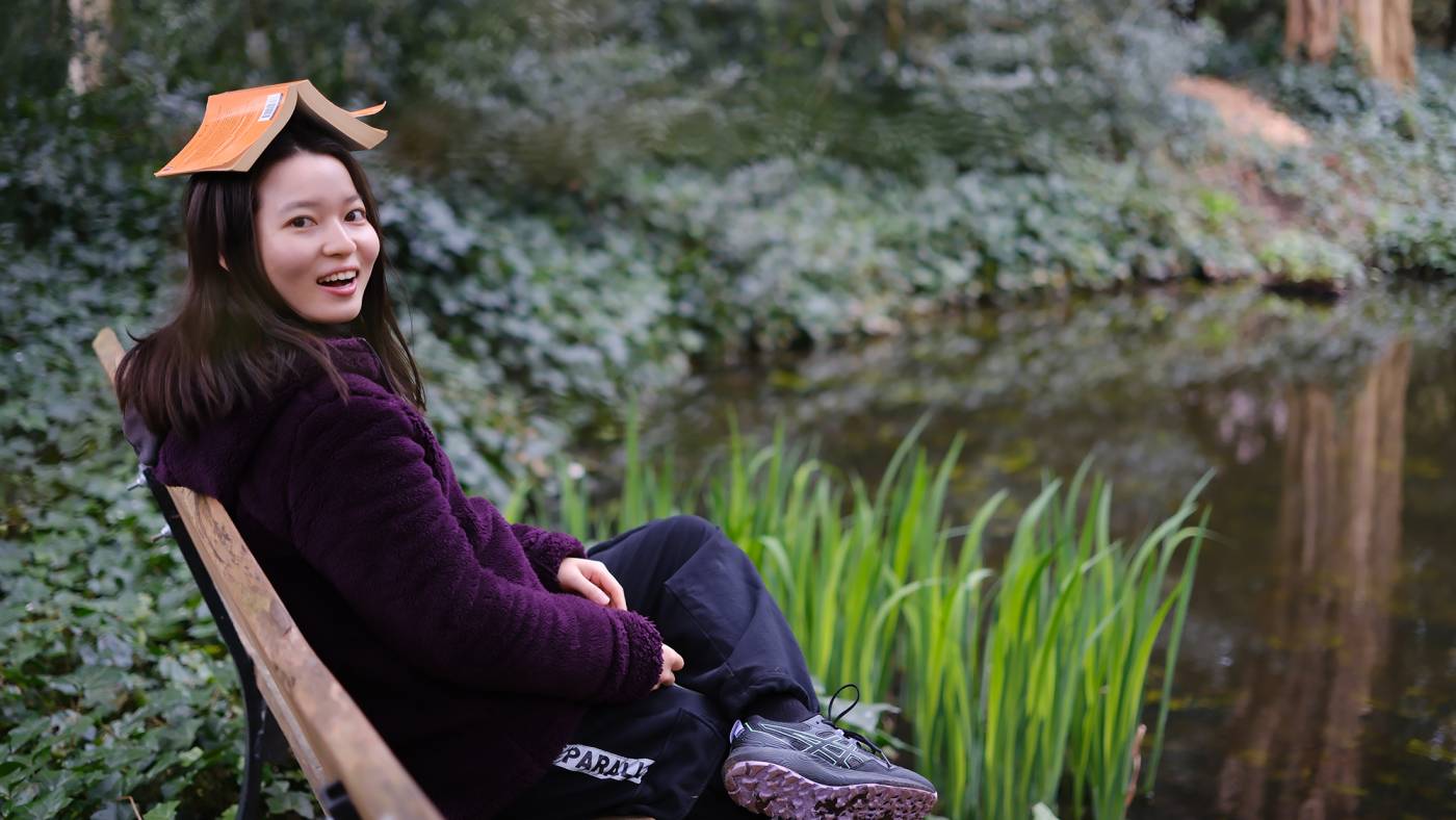 Xuanhao sitting in the garden with a book on her head