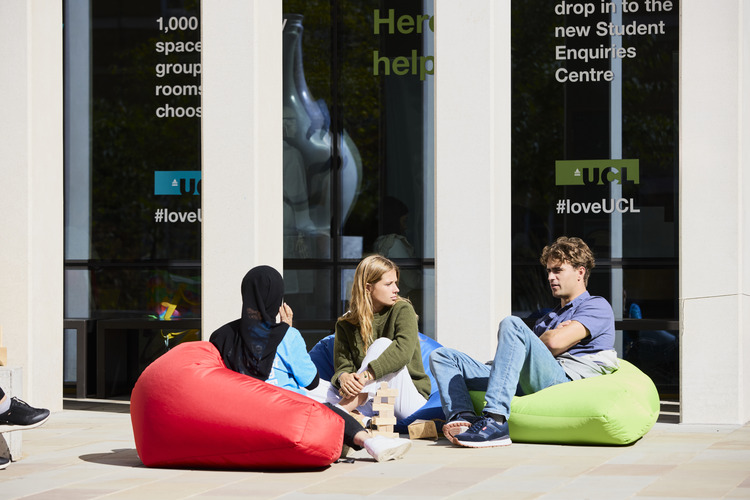 three students on bean bags outside student centre