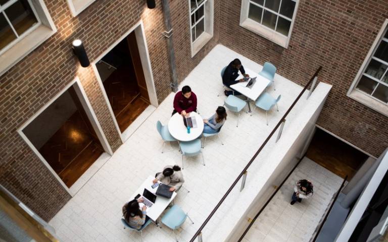 Bentham House hub and stairs, with students sitting around tables and studying