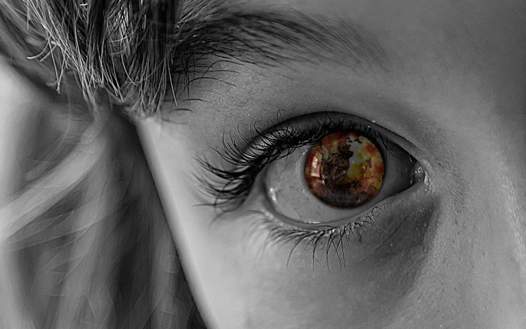 Image of a child's eye up close with the image of war reflected in their eye