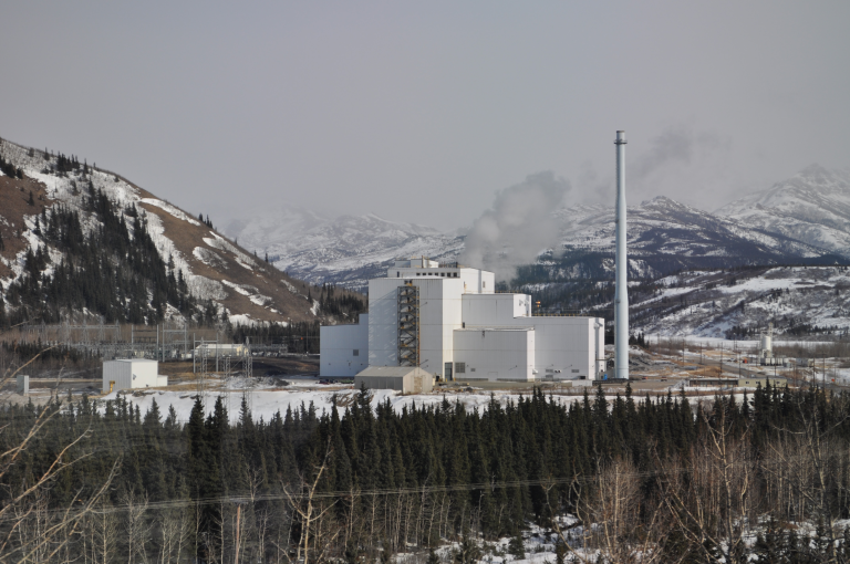Power plant in the middle of the forest with mountains in the background