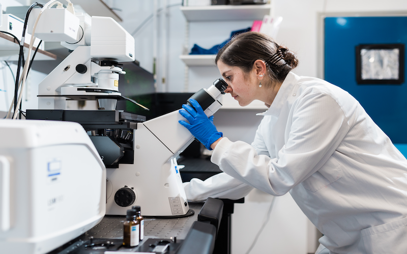 scientist looking down microscope