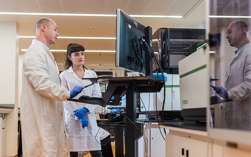 Two scientists with labcoats looking at computer