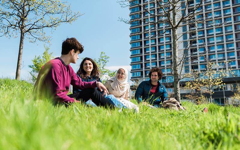 Students outside building sitting in grass