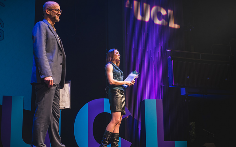 Two people facing a stage with lights behind them