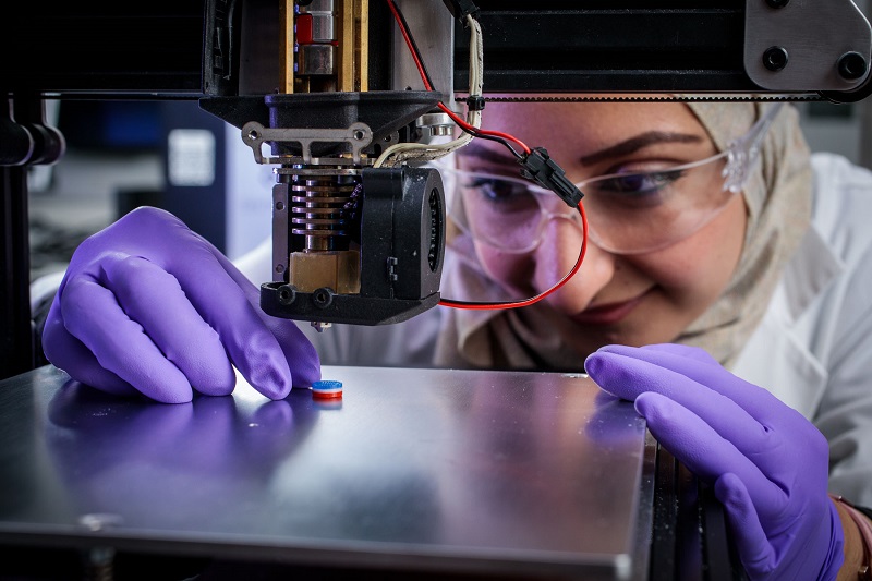 Researcher looking at printed tablet on 3D printer