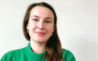 Alice wears a bright green jumper and smiles in this professional headshot