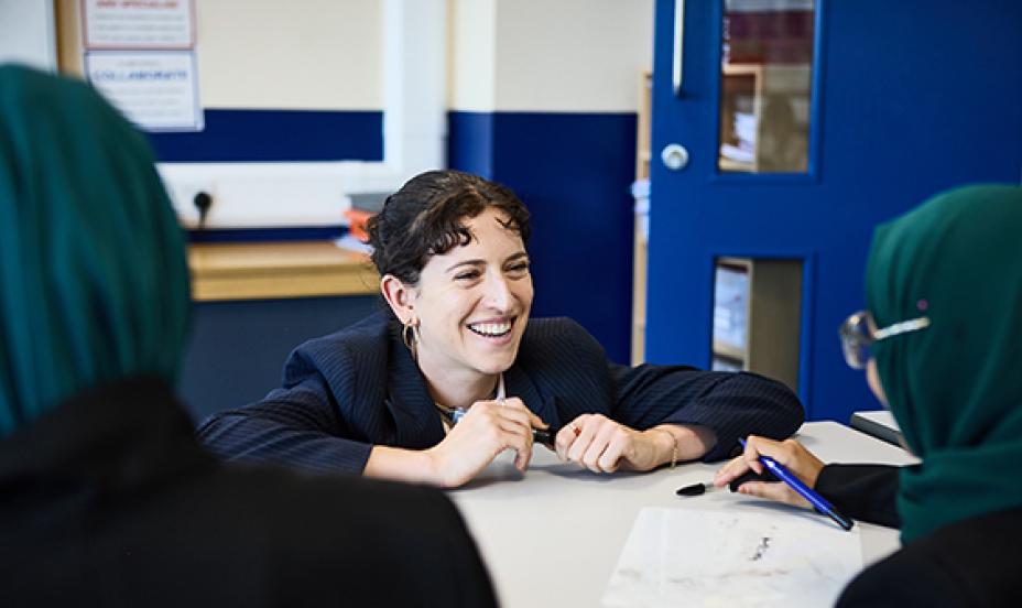 smiling teacher in classroom talking to students