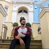 Alumni student Harsh sitting on steps in front of house