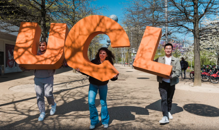 Three students outside carry the letters of UCL in giant orange shapes.
