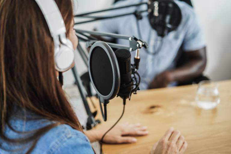 Woman wearing headphones being interviewed in front of a microphone