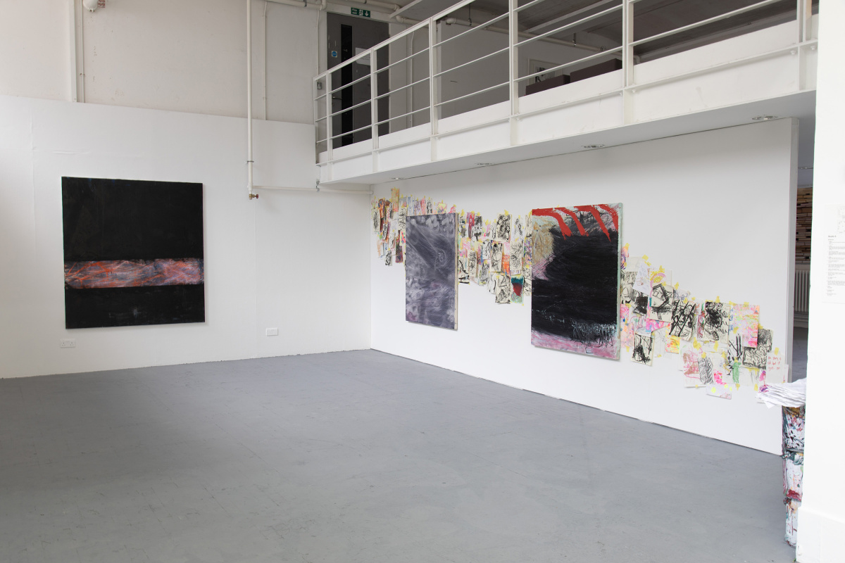 Installation photo of abstract paintings and drawings on wall.