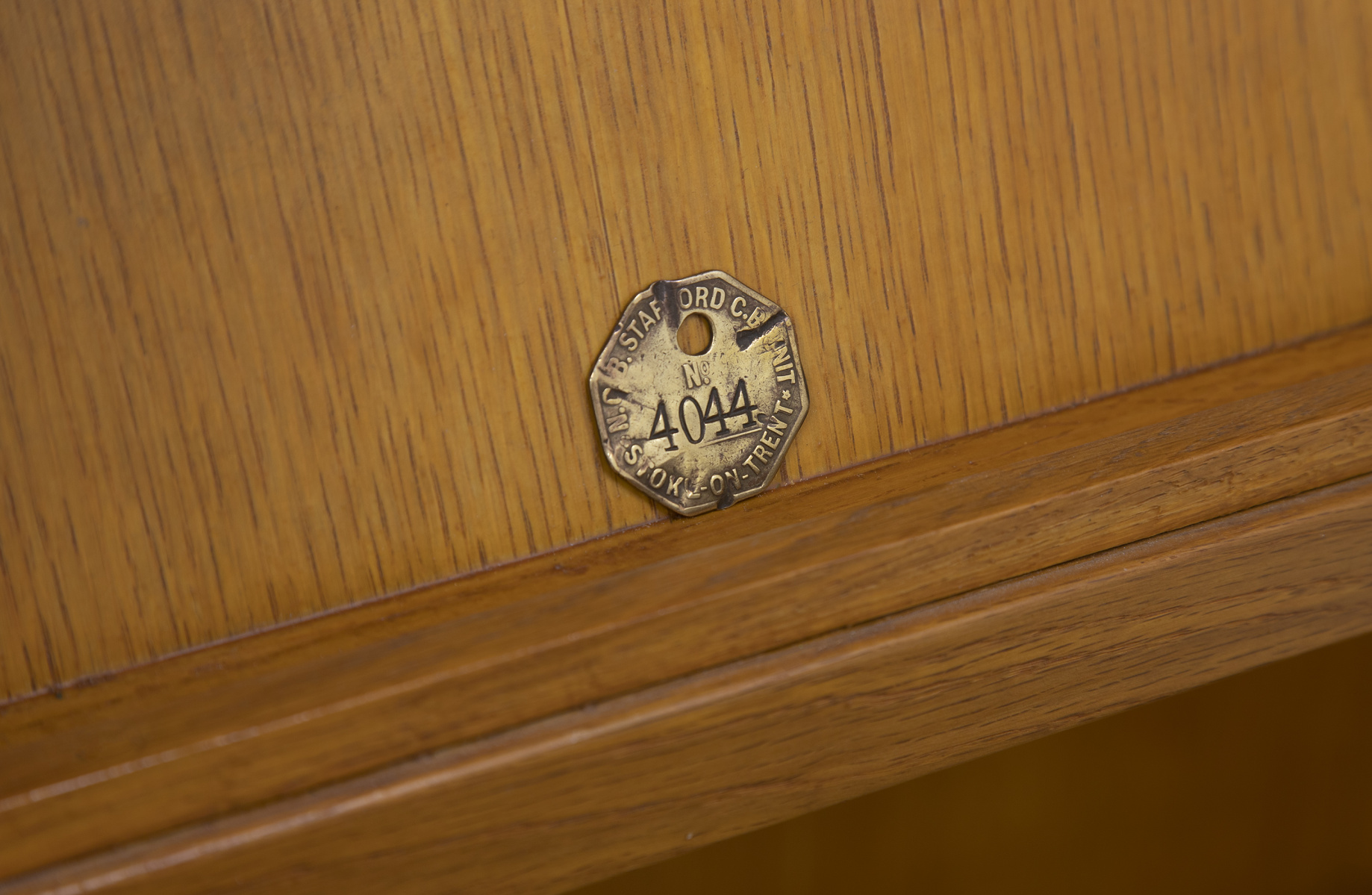 Close up of wooden shelf with small brass token.