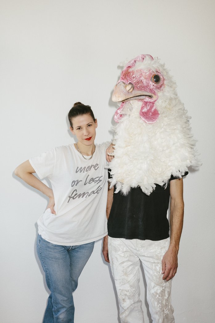 Photograph of a woman standing next to a person wearing a chicken head.