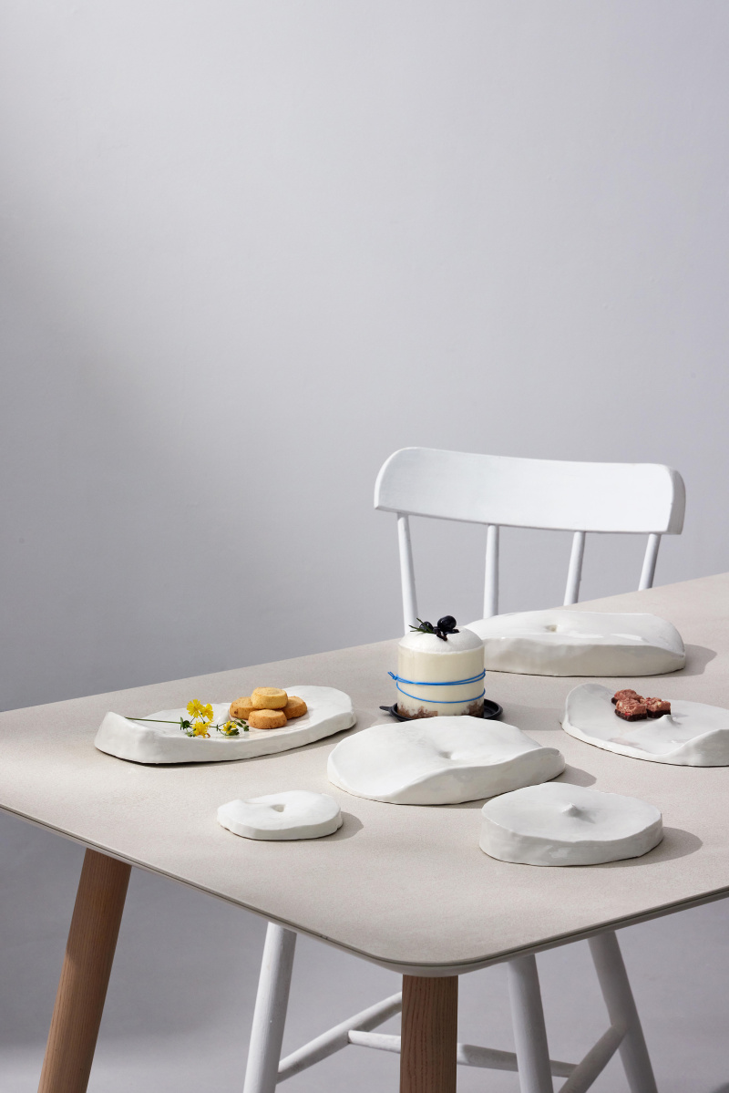 Table with 6 white belly button plates (2 with food on them), and chair.