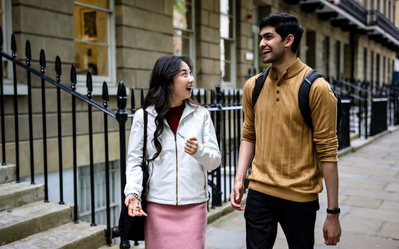 Image shows two students walking and laughing together