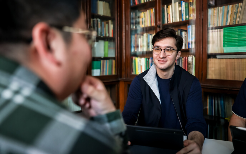 Image shows a student smiling at another student