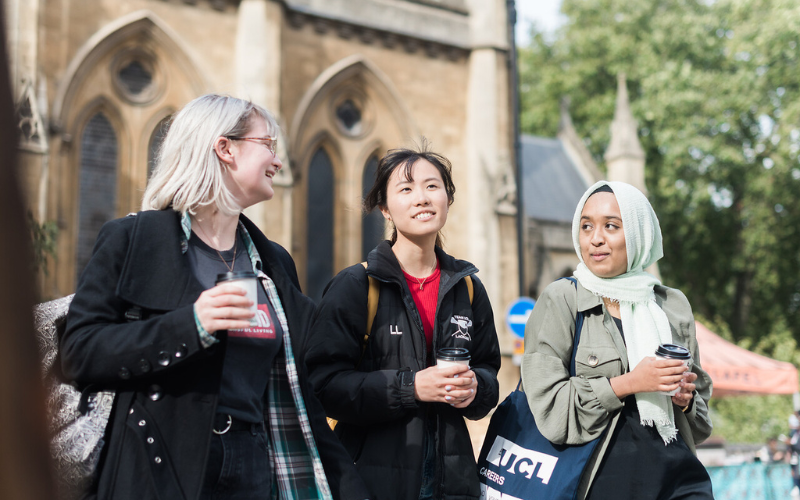 Image shows students walking, all holding a travel coffee mug 