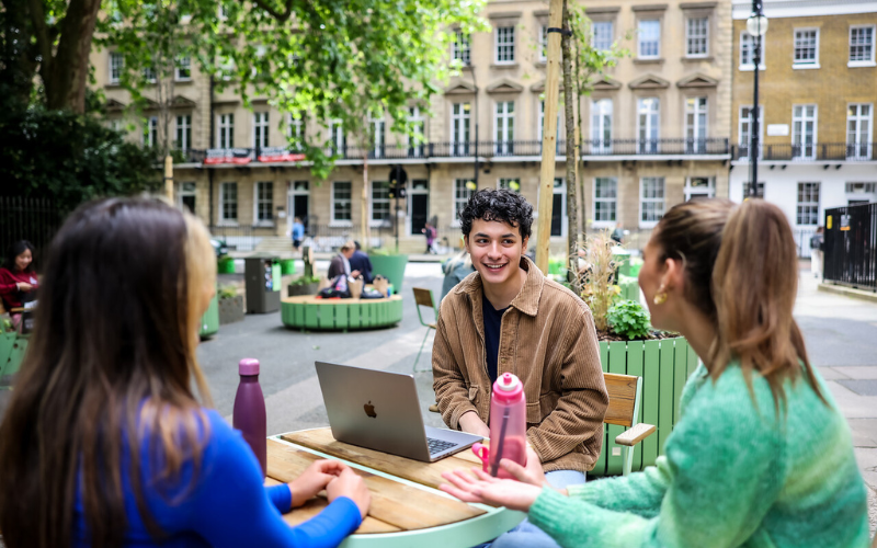 Image shows three students sitting outside Gordon Square