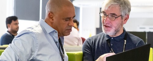 Two colleagues chatting over a laptop