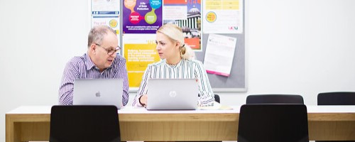 Two colleagues chatting over a laptop in Bidborough House